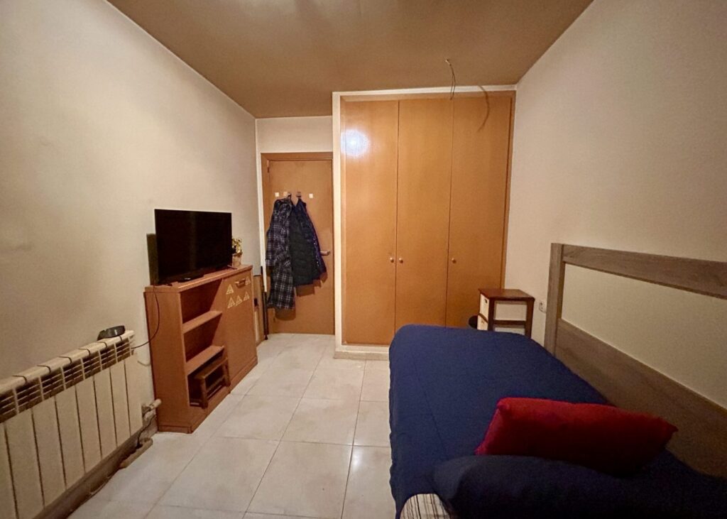 Dormitorio con armario y televisor