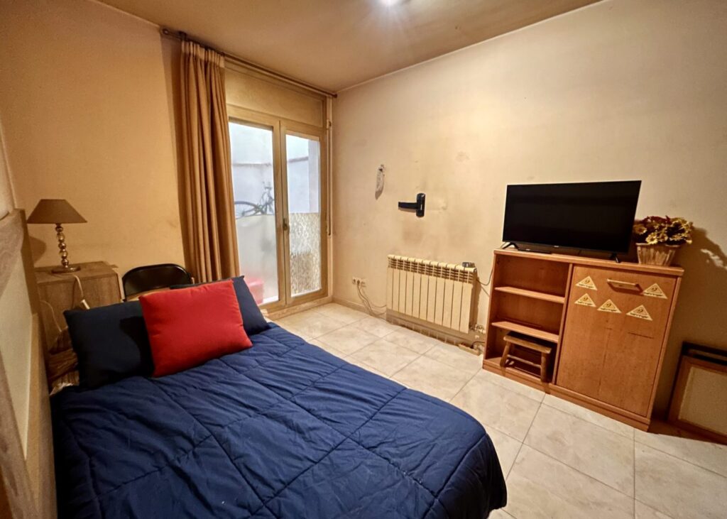 Dormitorio con mesita y televisor